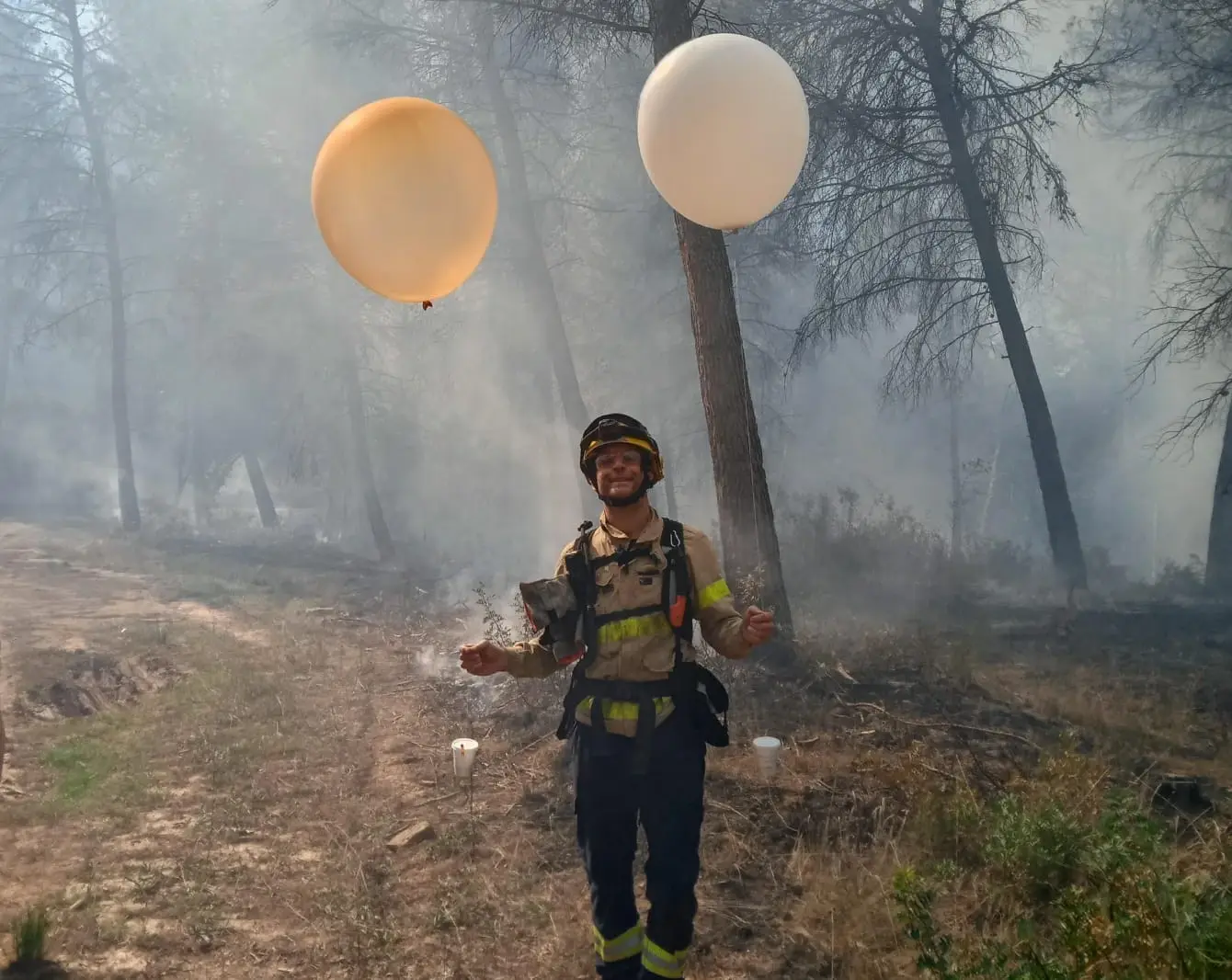 Firefighter ready to release two windsond next to a wildfire.